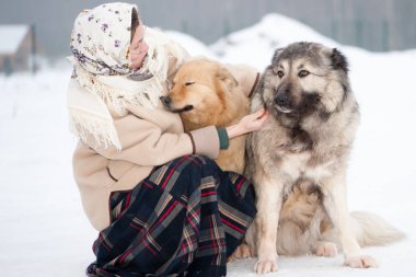Kız kış aylarında ormanın ortasında bir karlı zeminde Köpek eğitiyor. Kız bir ceket, uzun yün etek ve eşarp. Beyaz Bahçe çitin arkasında koruyan çoban.
