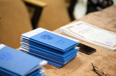 Tablonun üst üste gözlük ve bir smarphone mavi mezuniyet diploması yığını lay