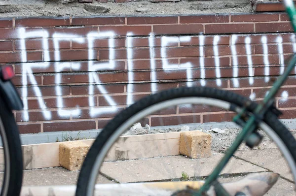 Üstünde o karanlık tuğla duvarına kelime Rebus beyaz boya bulunmakta. Bisikletin ön tekerlek ön planda olduğunu.