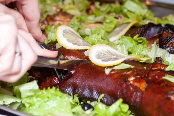 Marul içinde pişmiş somon limon dilimleri altında bırakır. Eller bir bıçak ve çatal tutun ve gövde Balık kesmek.