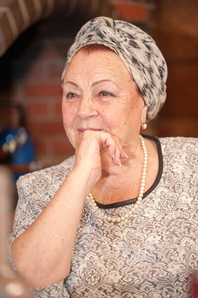 Portrait of elegant elderly lady sitting at the holiday table on the background of home interior