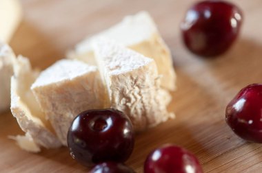 Keçi sütünden camembert tatlı kiraz çilek yakın çekim ile ahşap bir tahta üzerinde hala hayat dilimleri halinde kesilmiş