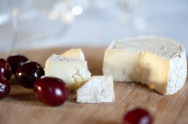 Keçi sütünden camembert tatlı kiraz çilek ile ahşap bir tahta üzerinde hala hayat dilimleri halinde kesilmiş. Planın üzerinde yatan net bir cam ile odak dışında