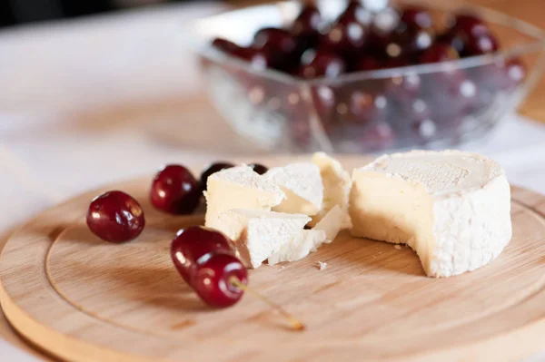 Keçi sütünden camembert tatlı kiraz çilek yakın çekim ile ahşap bir tahta üzerinde hala hayat dilimleri halinde kesilmiş