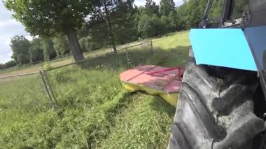 Bir çim biçme makinesi ile Traktör çitle çevrili ağaçlar, çit arkasında meşe ve çam etrafında sürücüler, yandan sapma ve kısmen biçilmiş çayır çıkmak