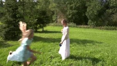 Bir köpek ve çocuk lu anne güneşli bir çimenlikte oynamaya geldi. Annem rulet tasmalı bir köpek salıyor. Çocuklar etrafta koşuşturun.