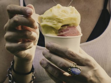 Bir yaz güneşli günde yeşil arka plana sahip bir Mango ve çilekli dondurma koni tutan insanlar