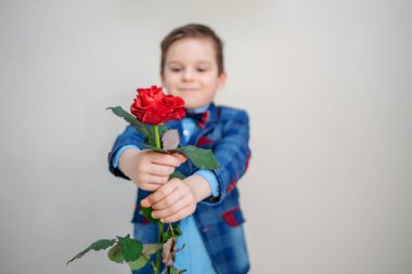 Hafif bir arka plan üzerinde kırmızı gül ile St Sevgililer günü kavramı ayakta takım elbiseli küçük çocuk
