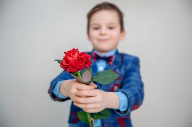 Hafif bir arka plan üzerinde kırmızı gül ile St Sevgililer günü kavramı ayakta takım elbiseli küçük çocuk