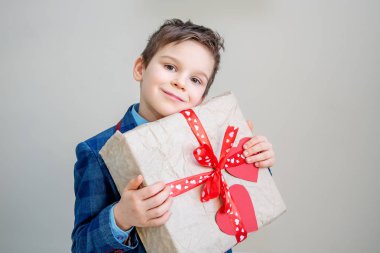 Açık renkli, st Sevgililer günü kavramı üzerinde bir hediye kutusu ile takım elbiseyle çok güzel çocuk
