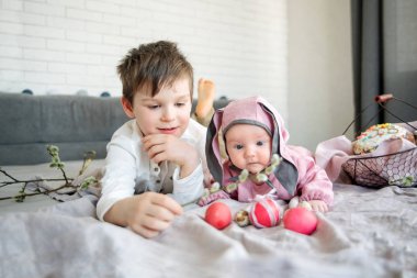 Keten battaniye var yalan ve Paskalya tavşanı ile yumurtalar söğüt dalları ve Paskalya pasta yakınındaki herbrother şeklinde bir şapka giymiş küçük bebek. Paskalya kutlamaları kavramı