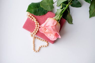 İnci kolye gül kadife kutu ve pembe bir gül. Açık renkli. Clouse-up.