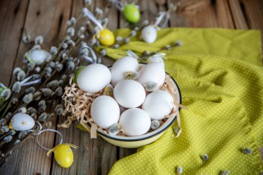 Ahşap masa üzerinde sarı plaka beyaz yumurta ile söğüt dallarında Paskalya yortusu yumurta