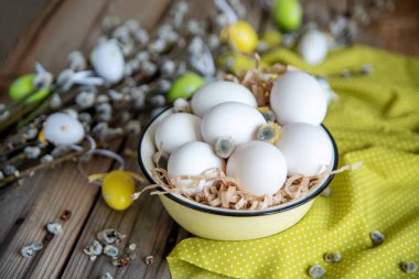 Ahşap masa üzerinde sarı plaka beyaz yumurta ile söğüt dallarında Paskalya yortusu yumurta