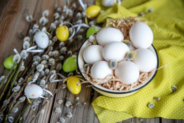 Ahşap masa üzerinde sarı plaka beyaz yumurta ile söğüt dallarında Paskalya yortusu yumurta