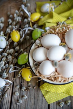 Ahşap masa üzerinde sarı plaka beyaz yumurta ile söğüt dallarında Paskalya yortusu yumurta