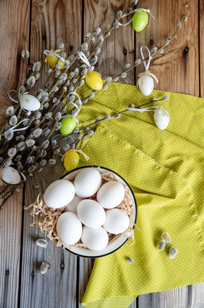 Ahşap masa üzerinde sarı plaka beyaz yumurta ile söğüt dallarında Paskalya yortusu yumurta