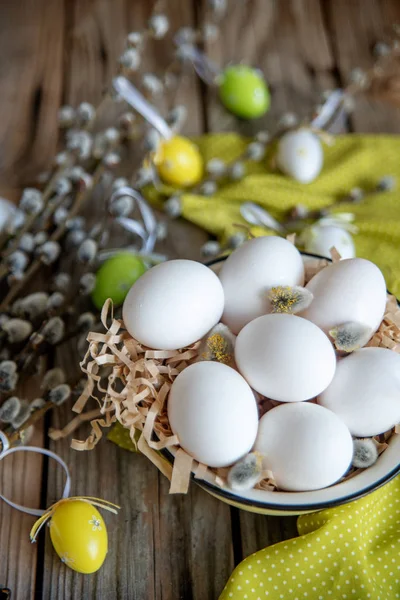 Ahşap masa üzerinde sarı plaka beyaz yumurta ile söğüt dallarında Paskalya yortusu yumurta