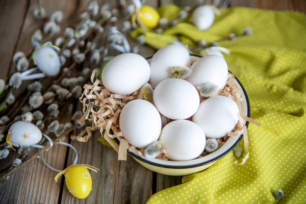 Ahşap masa üzerinde sarı plaka beyaz yumurta ile söğüt dallarında Paskalya yortusu yumurta
