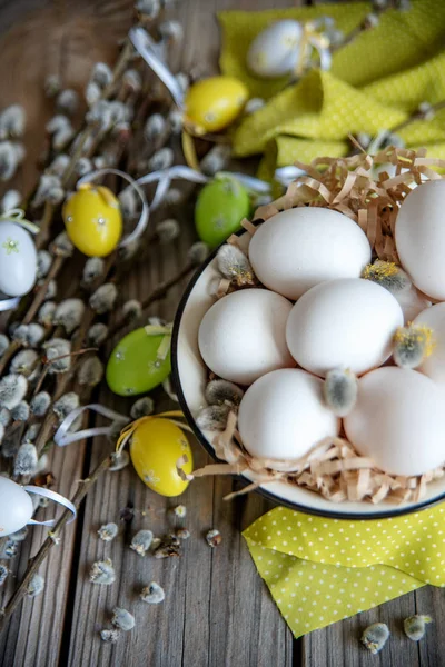 Ahşap masa üzerinde sarı plaka beyaz yumurta ile söğüt dallarında Paskalya yortusu yumurta