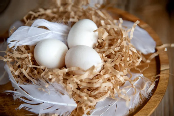Witte eieren in een decoratieve nest op een houten plaat. Pasen concept Pasen stemming. — Stockfoto