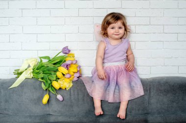 Lale peri elbise ile küçük kız yatakta oturur. Bahar ruh hali