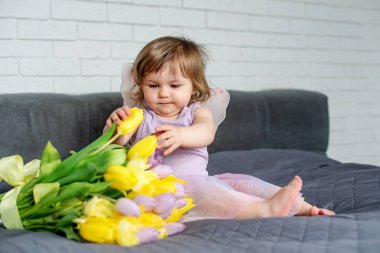 Lale peri elbise ile küçük kız yatakta oturur. Bahar ruh hali