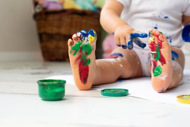 Küçük sevimli kız katta parmak boyaları ile çizer. Erken gelişim kavramı