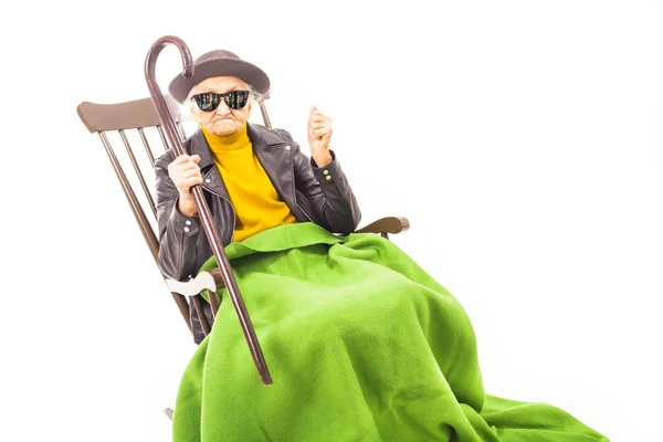 戴着帽子和太阳镜的老太婆坐在椅子上 上面有绿色的毯子 — 图库照片