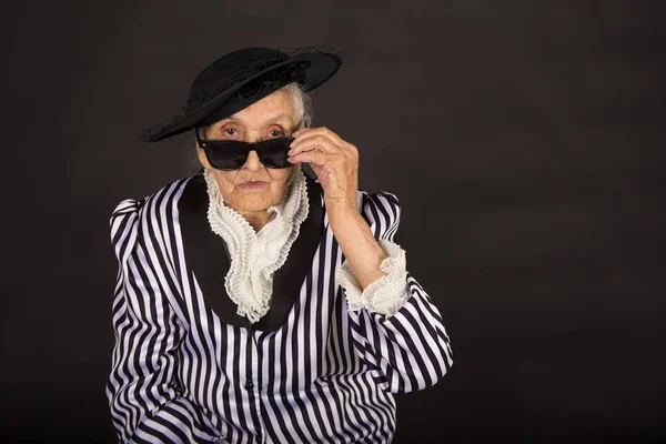 Stylish old woman on black background