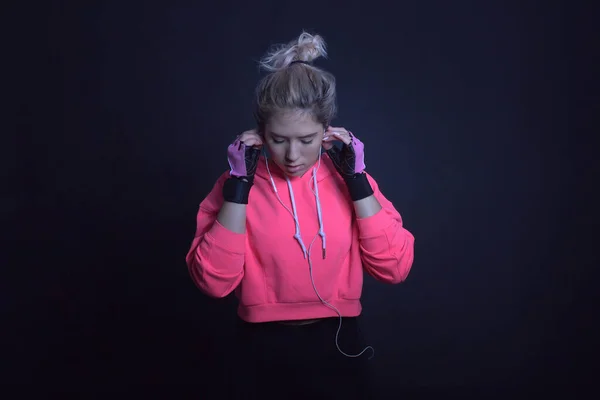 ピンクのパーカーの女性はヘッドフォンを使い ロイヤリティフリーのストック写真