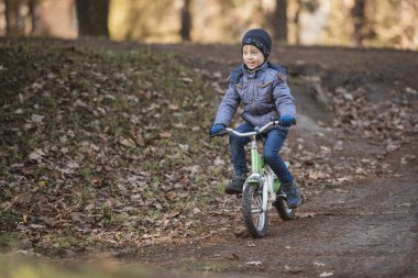 Altı yaşında bir çocuk parktaki tepeden bisiklete biniyor..