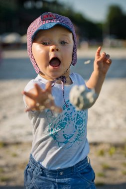 Bir kum topu atma iki yaşında bir çocuk