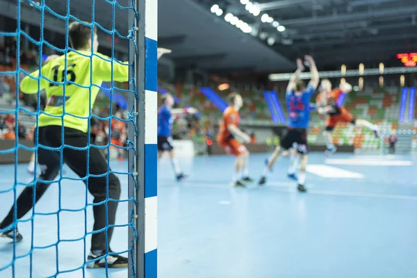 Hentbol kale direğinin ayrıntıları ve arka planda hentbol maçı.