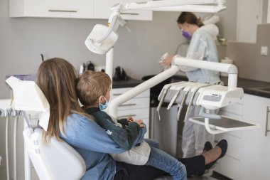 Annesinin kucağında oturan çocuk Covid-19 salgını yüzünden yüz maskeleri var..