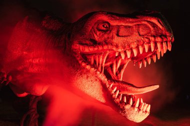 LUBIN, POLAND - AUGUST 15, 2020 - lluminated realistic model of dinosaur Tyranosaurus Rex in Park Wroclawski during Museum Night. clipart