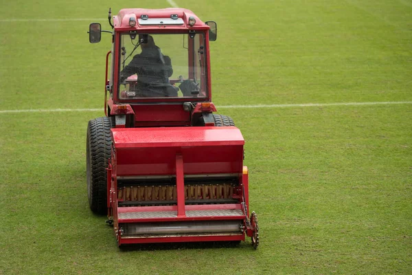 A man in a tractor with a disc seeder drill sowng grass on a football field — Stock Image Man Tractor Disc Seeder Drill Sowng Grass Football Field Royalty Free Stock Photos