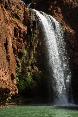 Faslı genç adam yüksek kayalıklardan bir şelalenin altındaki suya atlıyor..