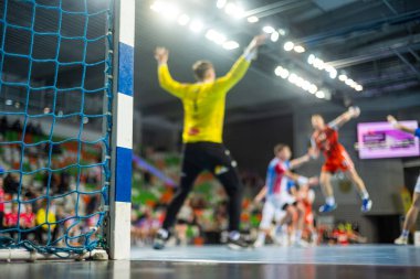 Hentbol kale direğinin ayrıntıları ve arka planda hentbol maçı.