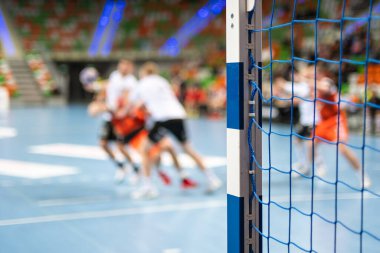 Hentbol kale direğinin ayrıntıları ve arka planda hentbol maçı.