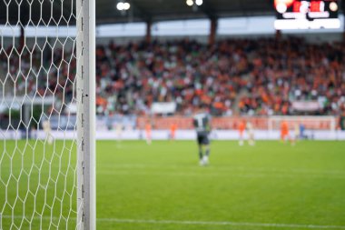 Futbol stadyumunda kale direği, arka planda oyun var.