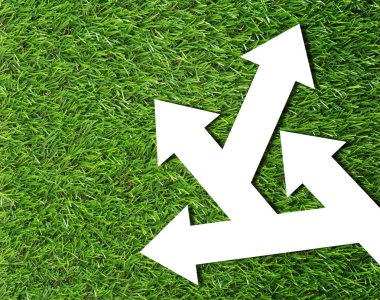 Business problem or confused concept, white arrow on green grass background clipart