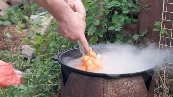 Draußen kochen. Ein Mann kocht Suppe im Kessel. — Stockfoto