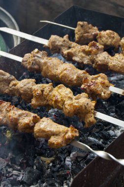 Sıcak kömürde kızaran etli şişler (Shashlik). Duman ve altın hamuru yemeği özellikle iştah açıcı yapar..