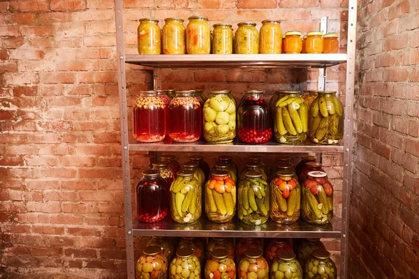 storage of vegetables and fruits for the winter. Shelving with banks with blanks in the home cellar.