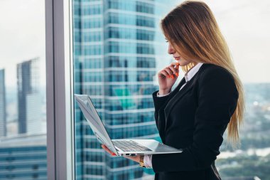 Düşünceli erkek CEO'su ayakta okuma ve düşünme bir laptop holding modern iş merkezi özel ofisinde penceresinde karşı