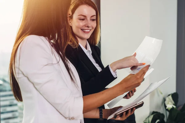 Vrouw en haar assistent holding documenten bespreken businessplan en strategie op werkplek — Stockfoto