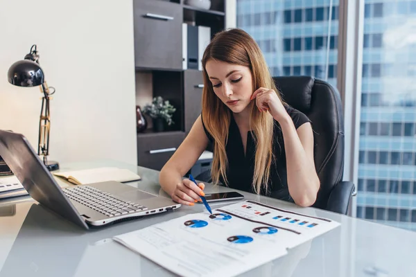 Donna d'affari rileggere rapporto finanziario che analizza le statistiche che indicano grafico a torta che lavora alla sua scrivania — Foto Stock