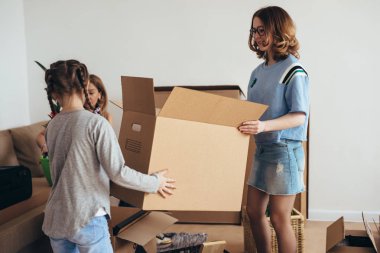 Karton kutular ile yeni evde iki çocuk annesi.