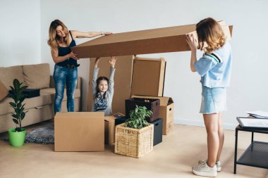 Karton kutular ile yeni evde iki çocuk annesi.